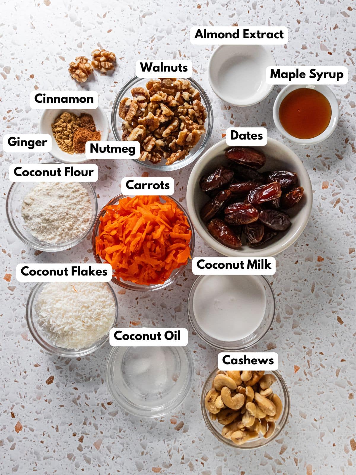 Ingredients to make this gluten-free carrot cake in bowls on a table.