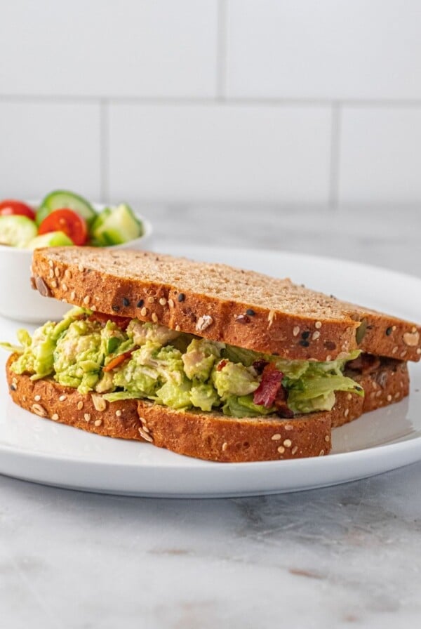 Guacamole chicken salad on two slices of bread on a plate.