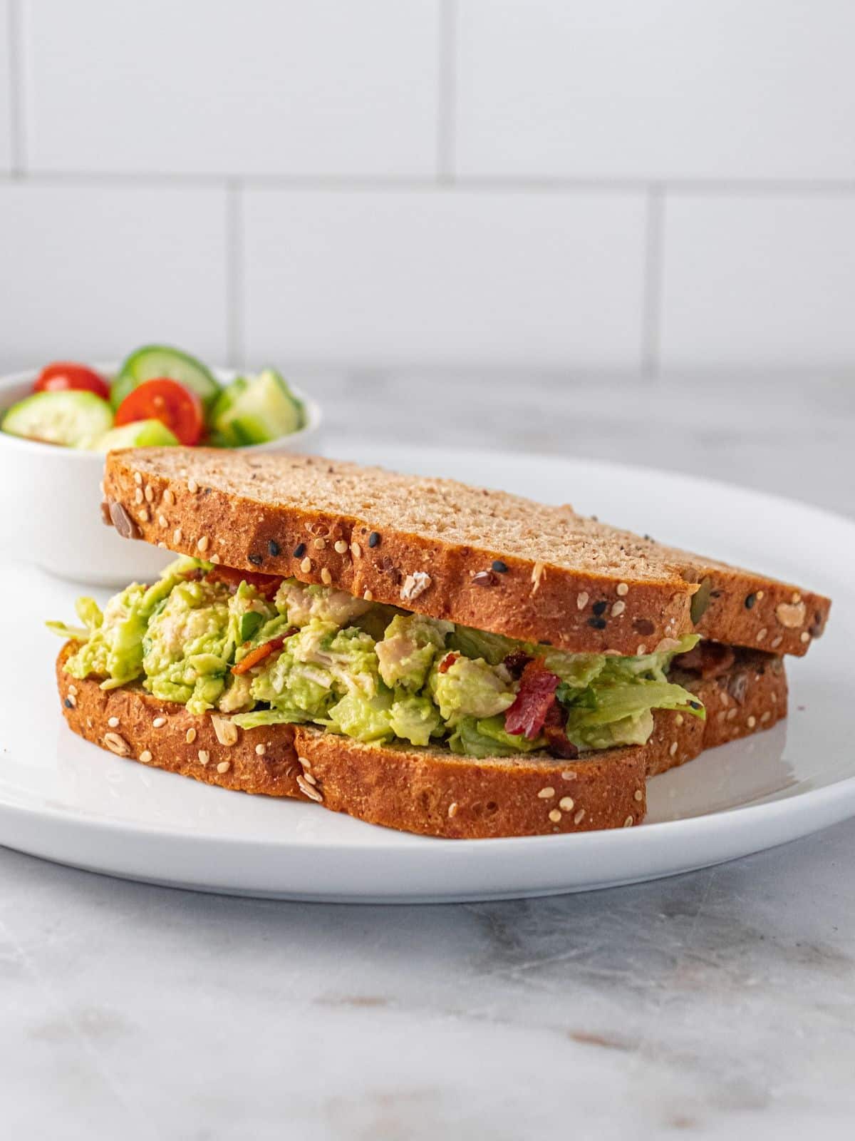 Guacamole chicken salad on two slices of bread on a plate.