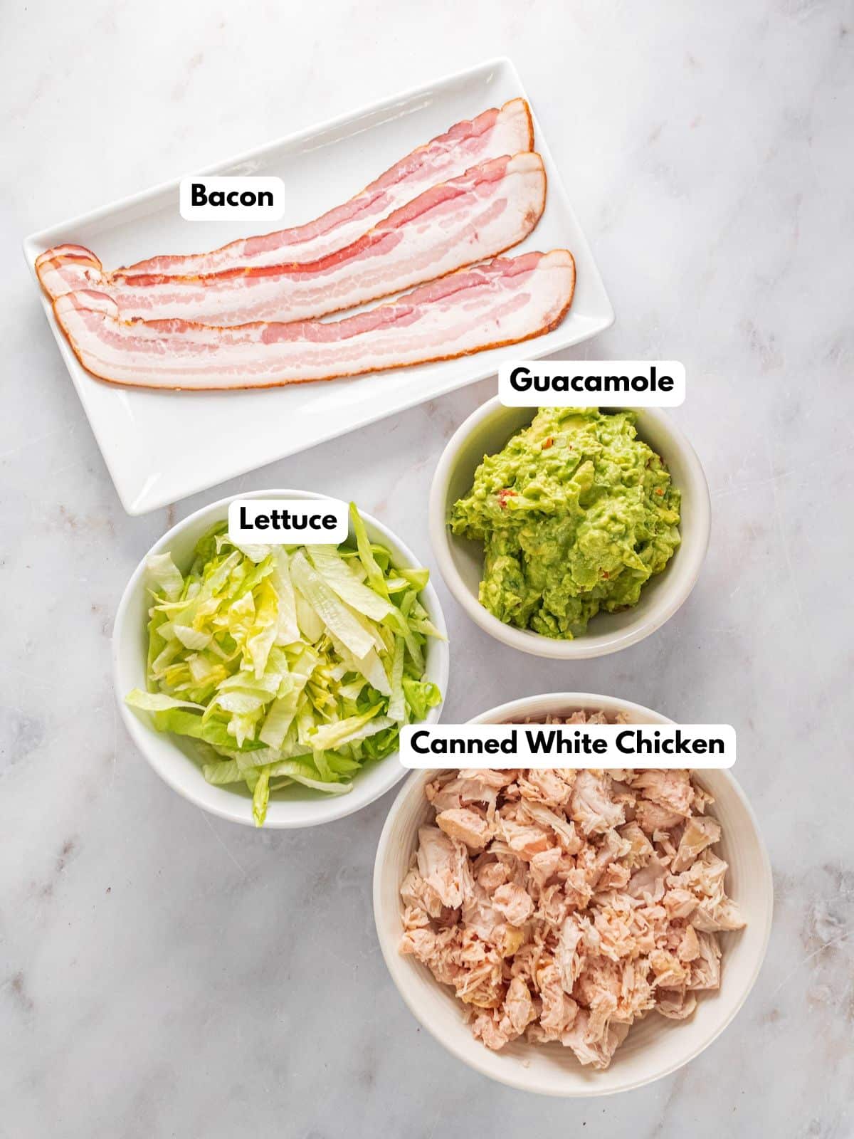 Ingredients to make this guacamole chicken salad in bowls on a table.
