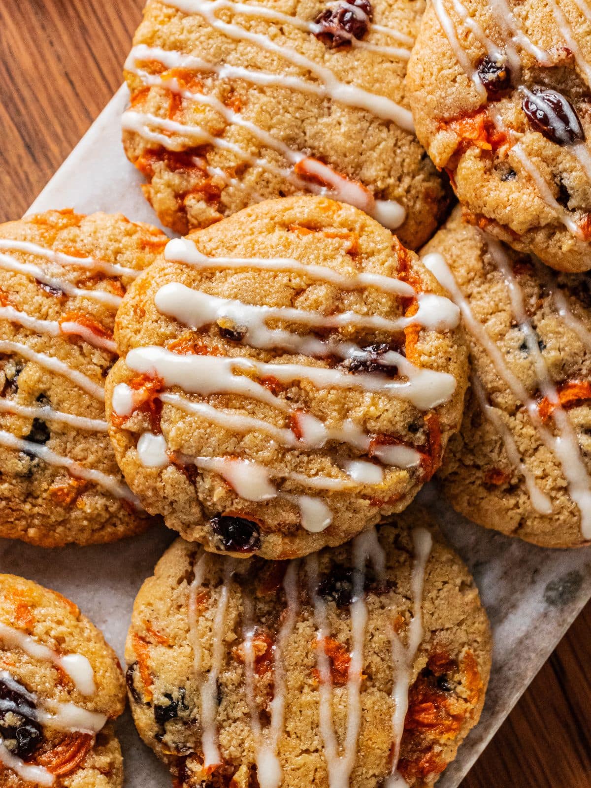 Healthy carrot cake cookies with icing on top stacked on top of each other.