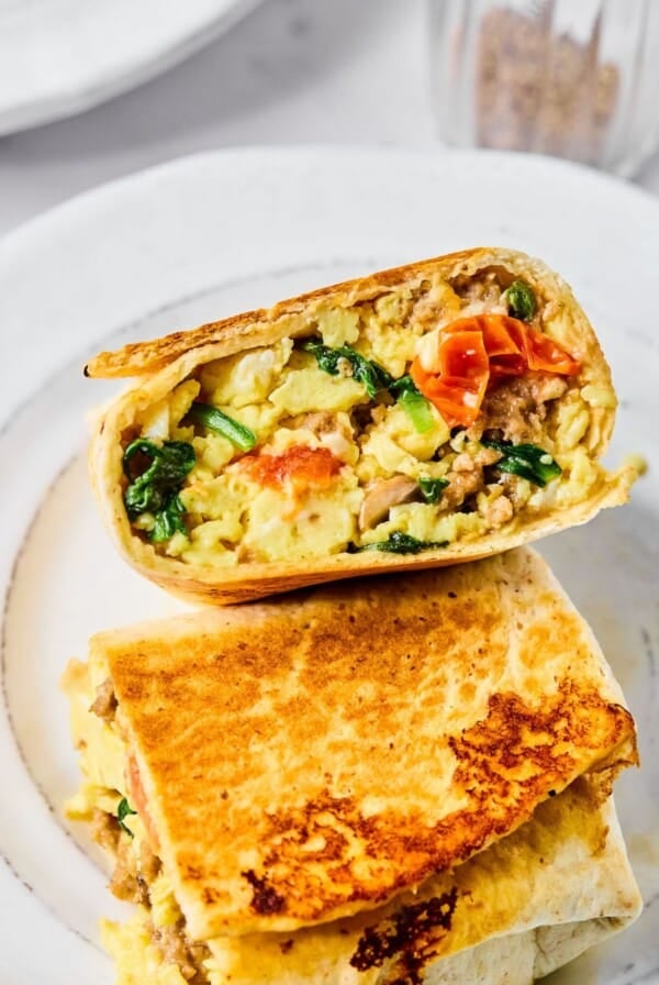 A plate with two halves of a breakfast burrito.