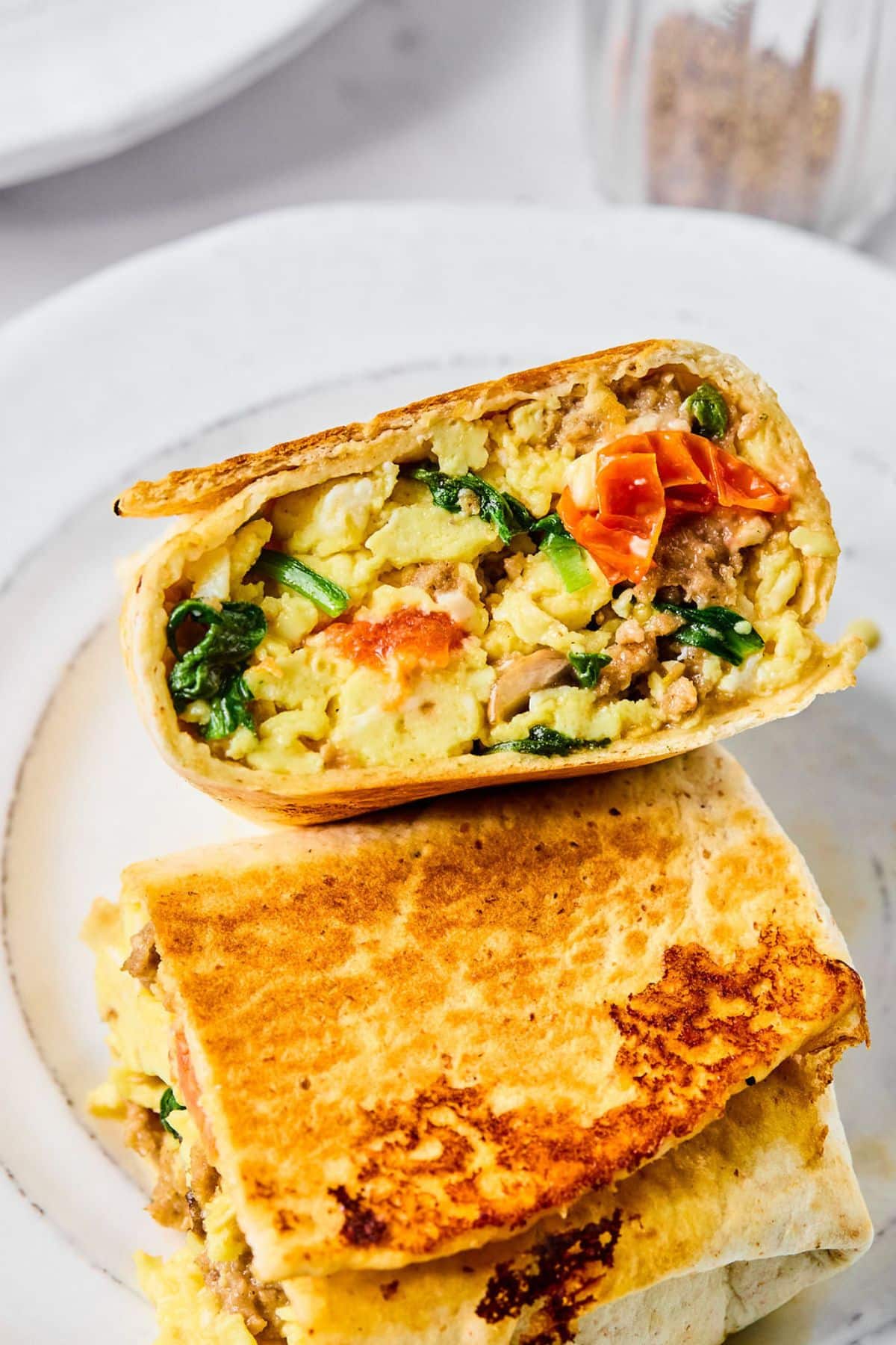 A plate with two halves of a high-protein breakfast burrito.