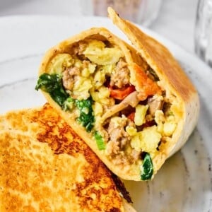 Half of a high-protein breakfast burrito on a white plate.