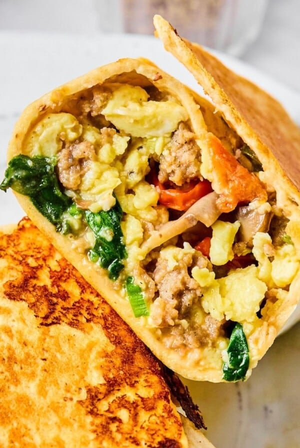 Half of a high-protein breakfast burrito on a white plate.