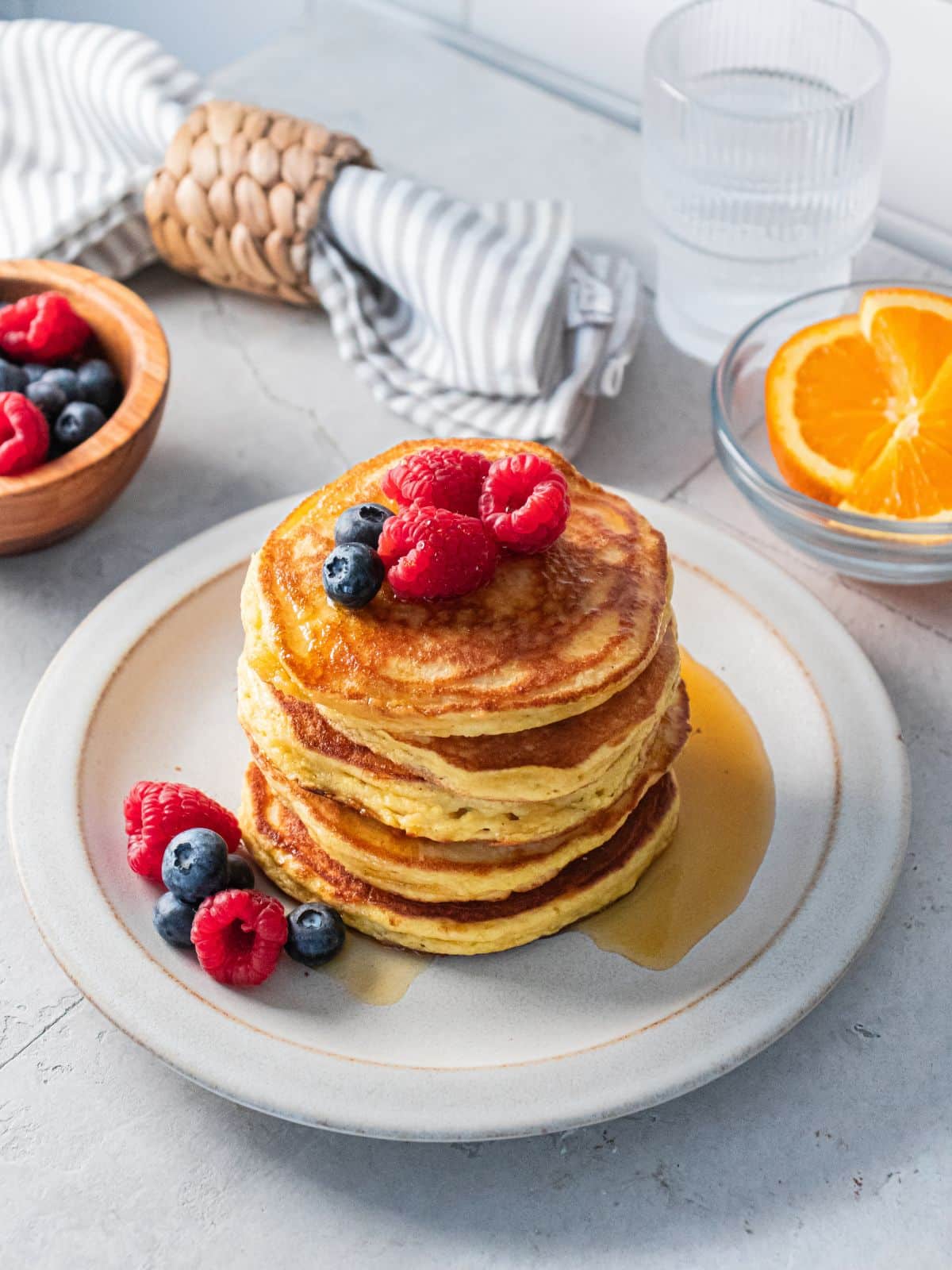 Almond pancakes on a plate with berries on top.