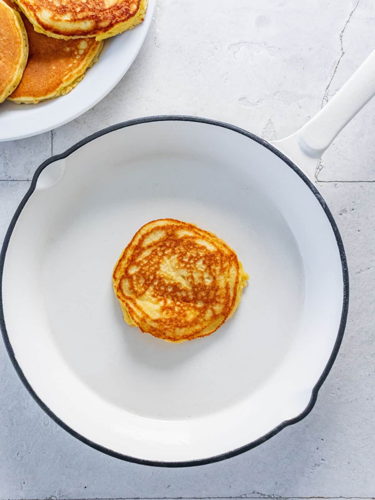 An almond flour pancake cooked in a pan.
