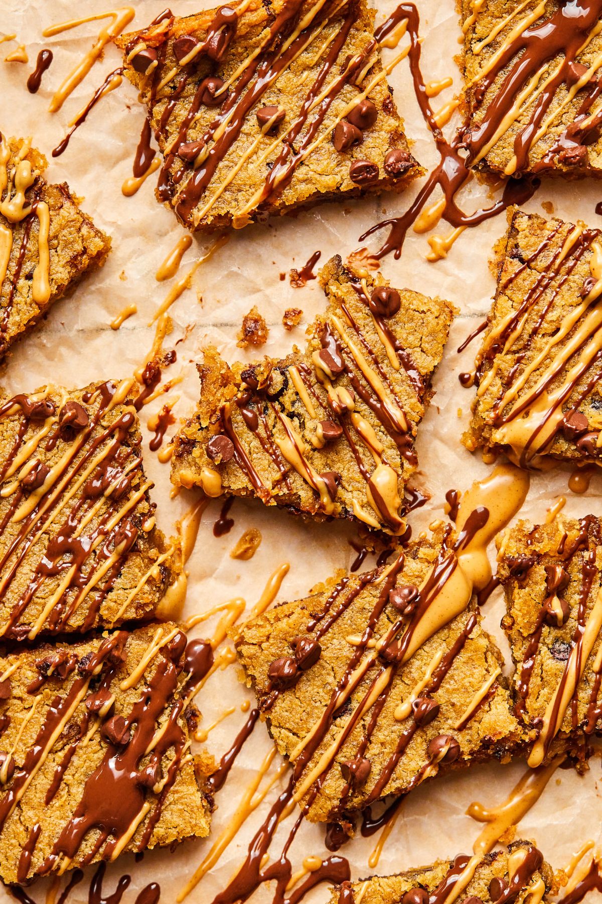 A bunch of chickpea blondies with some chocolate and peanut butter drizzled on top.