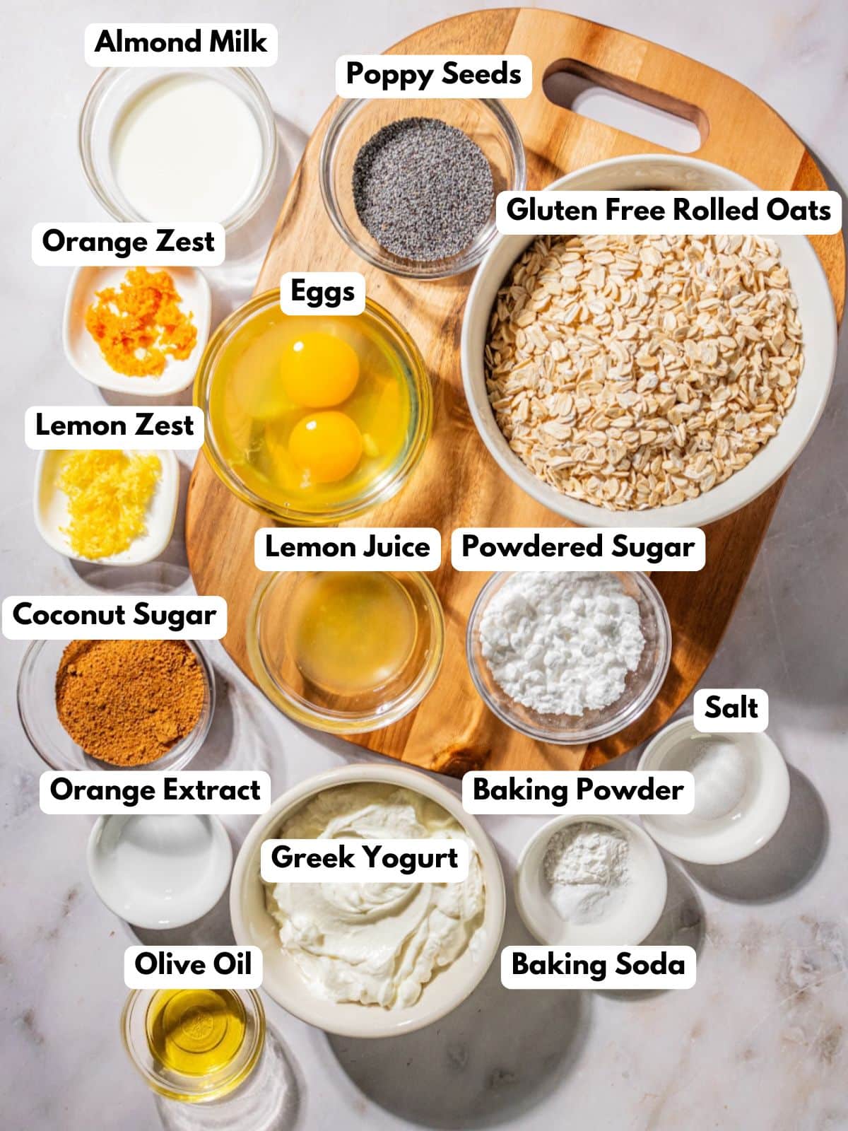 Ingredients to make these poppy seed muffins in bowls on a table.