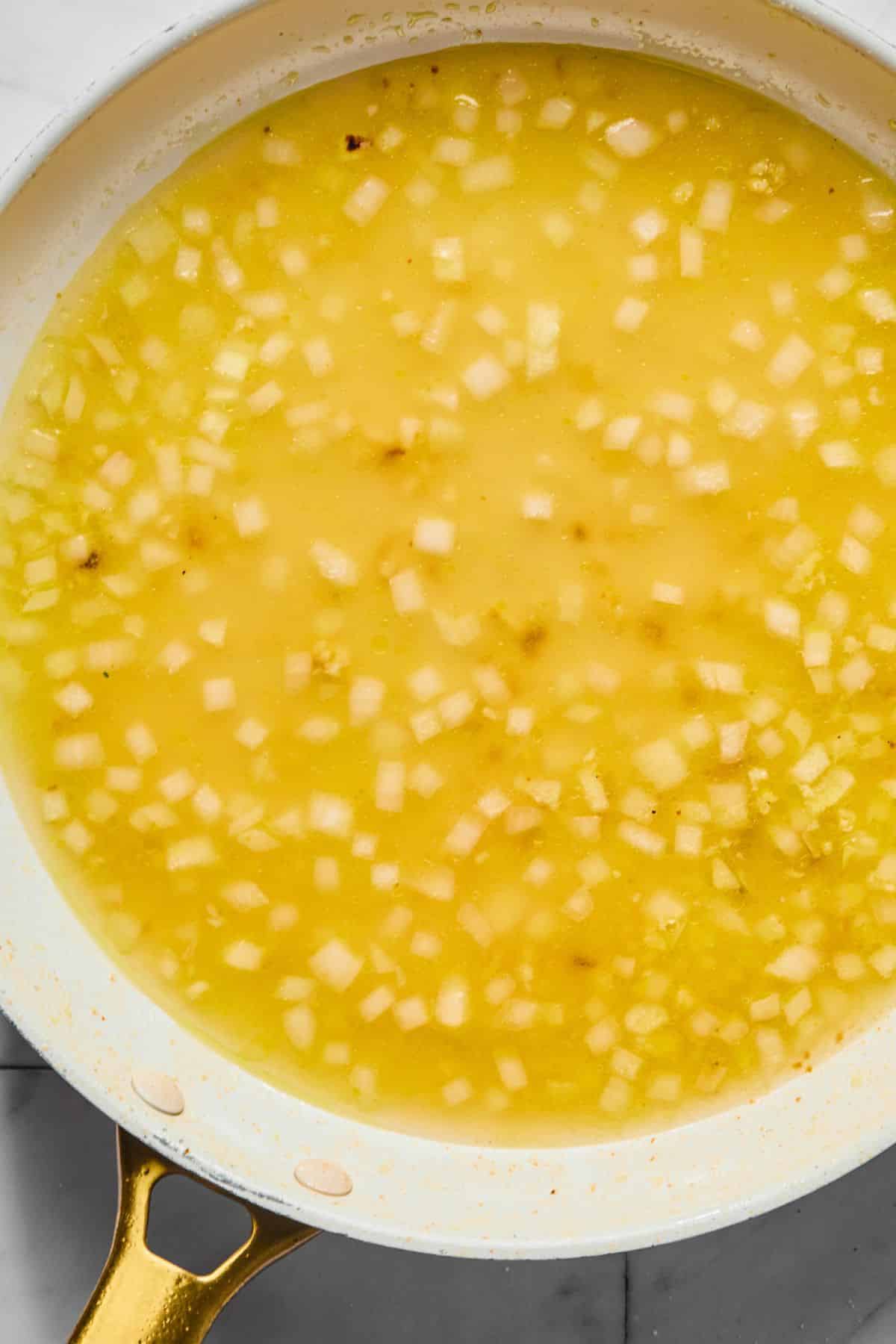 Chicken broth and lemon juice added to the skillet.
