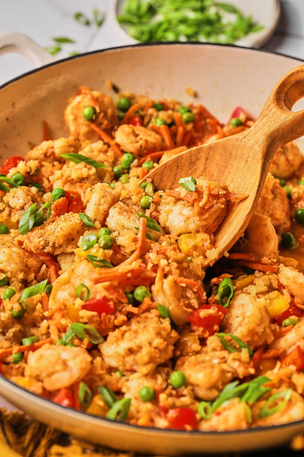 A wooden spoon scooping outs some healthy shrimp fried rice.