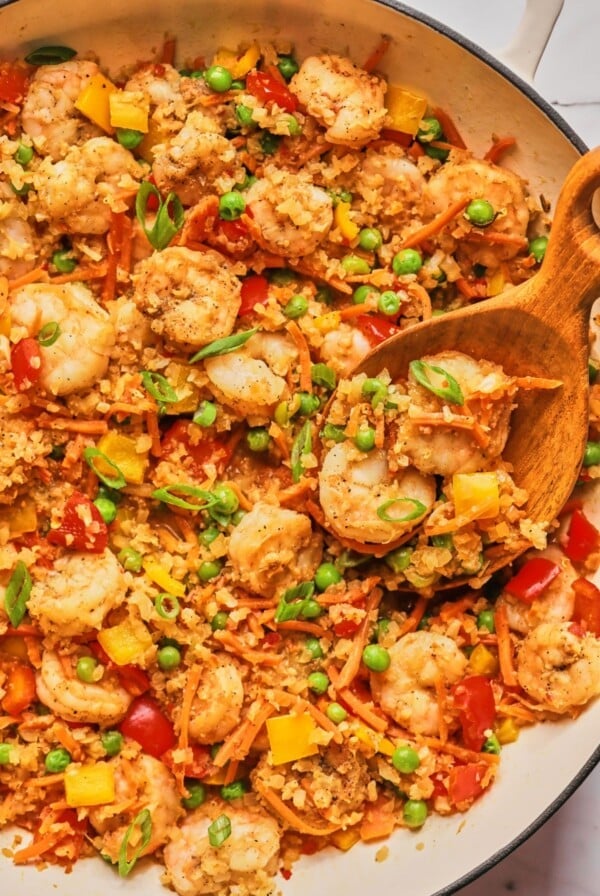 Shrimp fried rice in a pan with a wooden spoon.