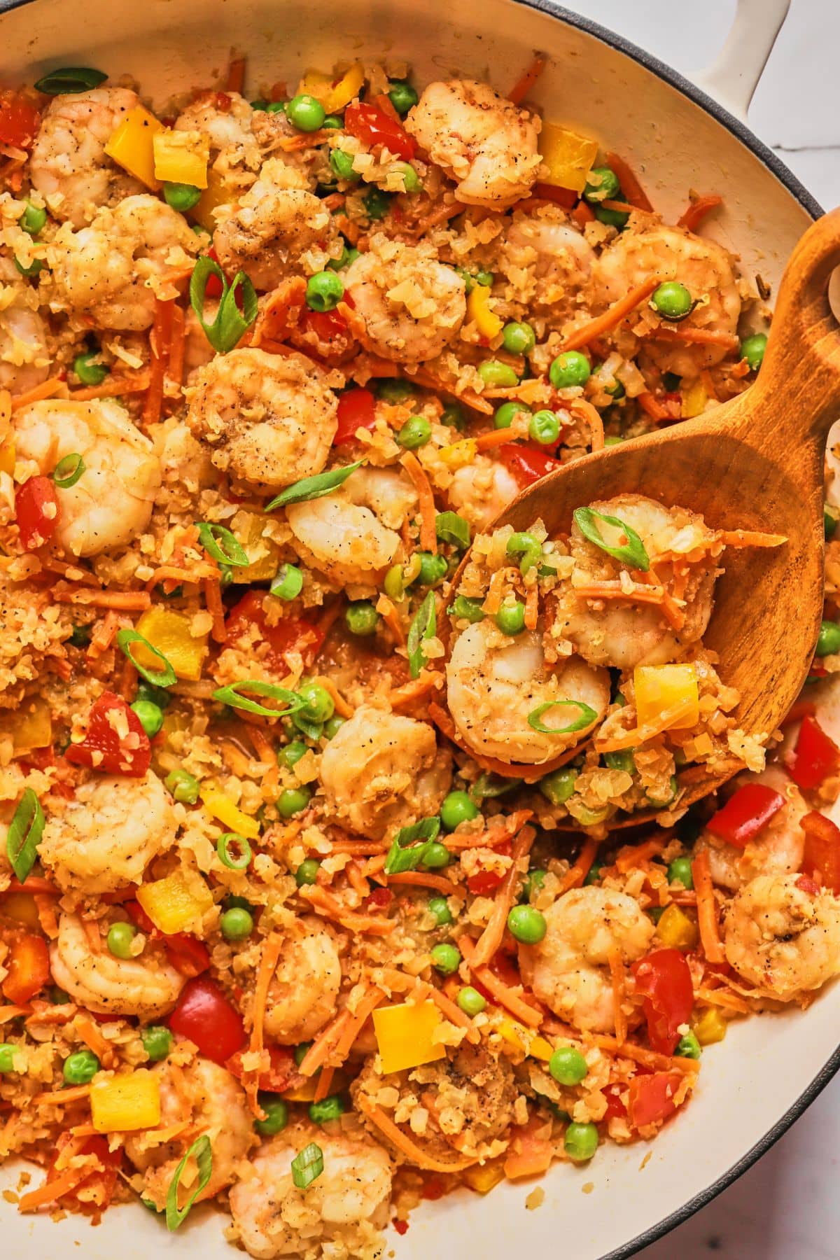 Shrimp fried rice in a pan with a wooden spoon.
