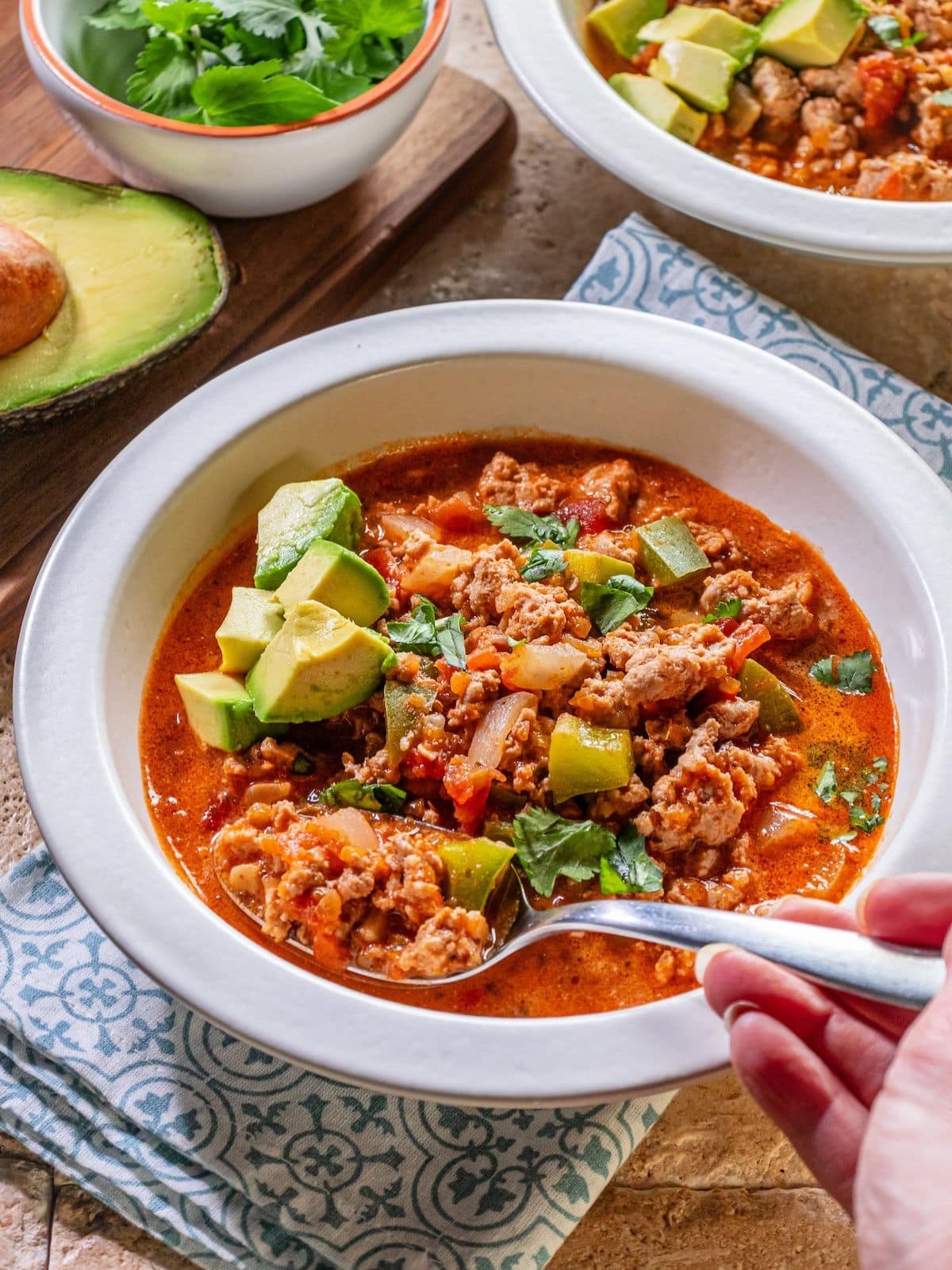 A spoon scooping out taco soup in a bowl.