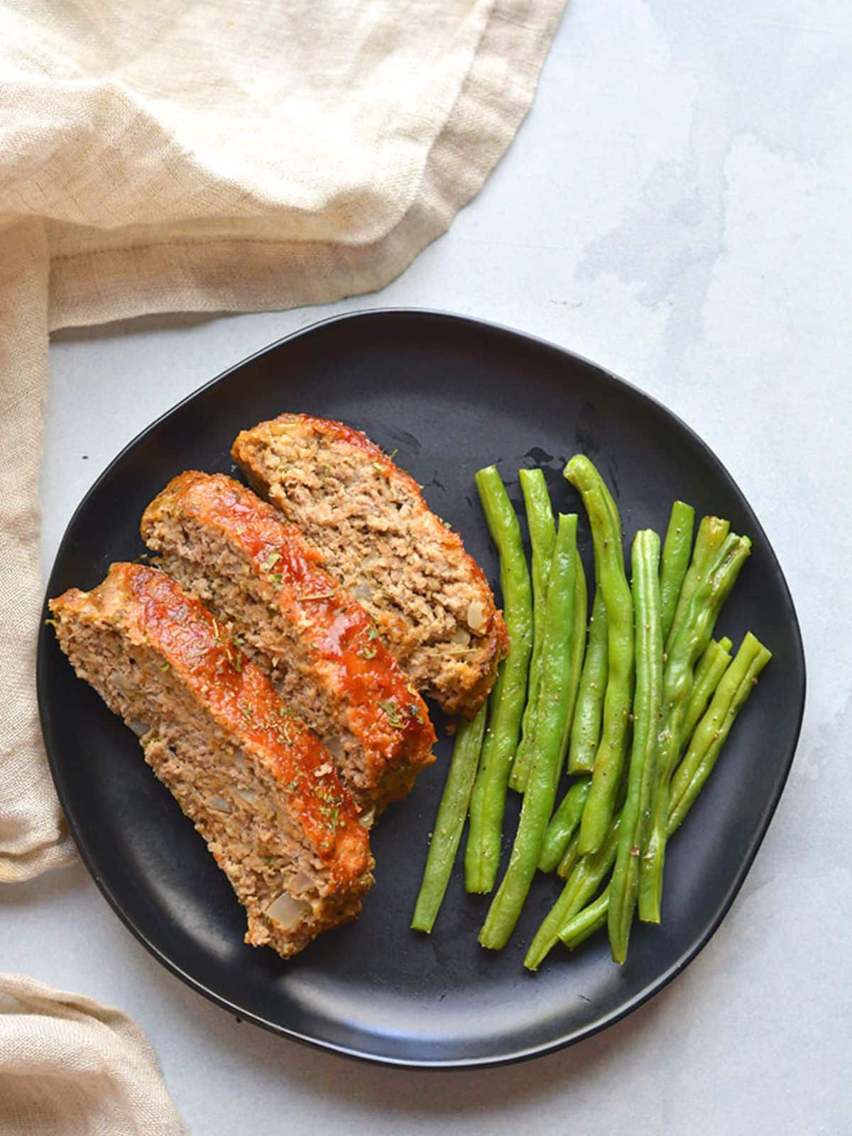 Healthy turkey meatloaf on a black plate.