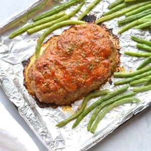 A healthy turkey meatloaf on a sheetpan with green beans.