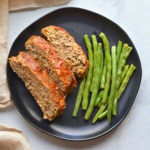 Healthy turkey meatloaf on a plate with green beans.