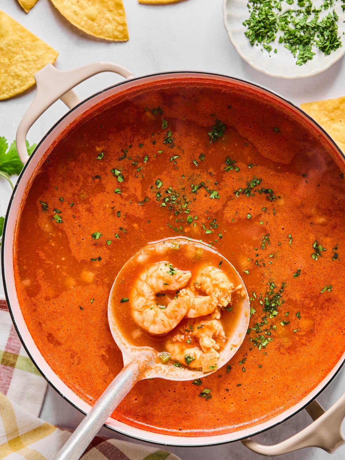 Shrimp in a ladle added to the soup.