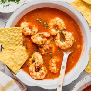 A bowl with Mexican shrimp soup in it and a spoon resting in the bowl.