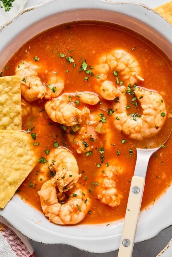 A bowl with Mexican shrimp soup in it and a spoon resting in the bowl.