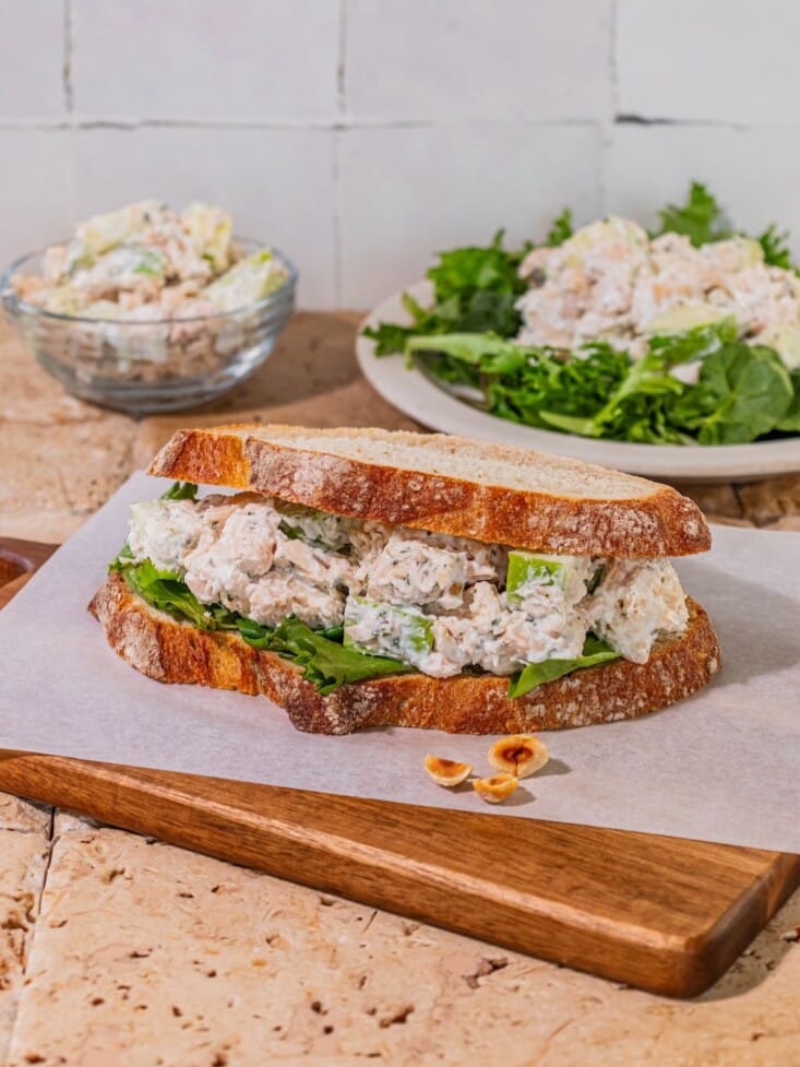 Apple chicken salad sandwich on a cuttinb board.