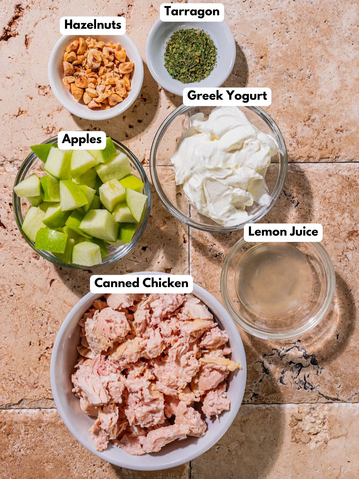 Ingredients to make this chicken salad with apples in bowls on a table.