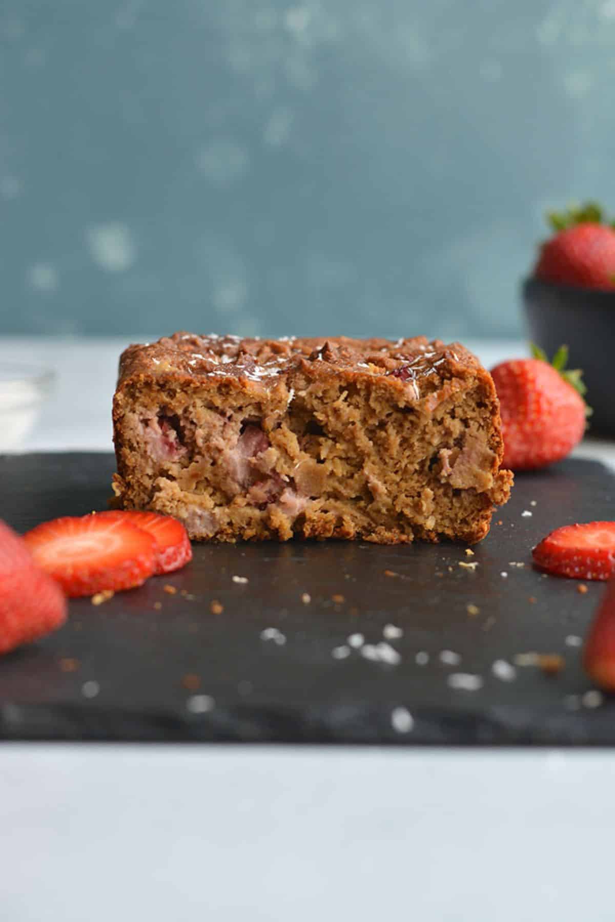 A slice of strawberry bread on a cutting board.