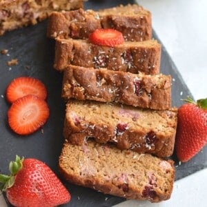 Banana strawberry bread in slices on a black cutting board.