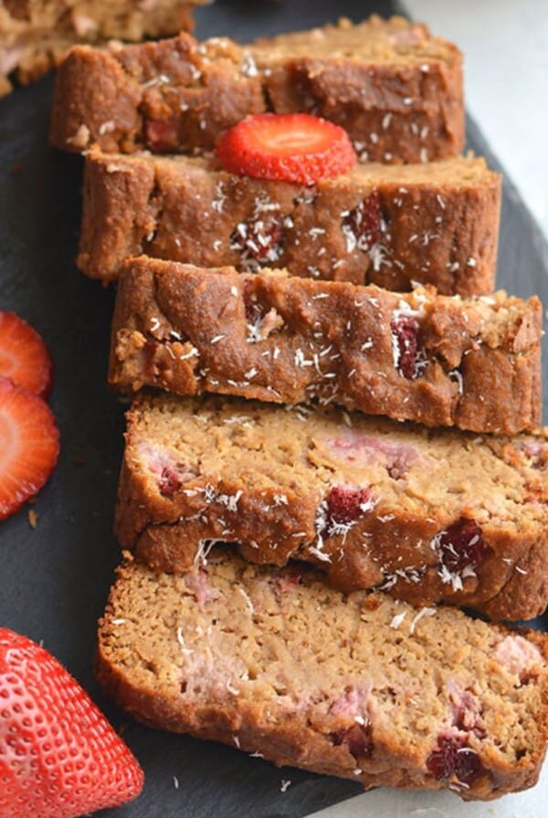 Banana strawberry bread in slices on a black cutting board.
