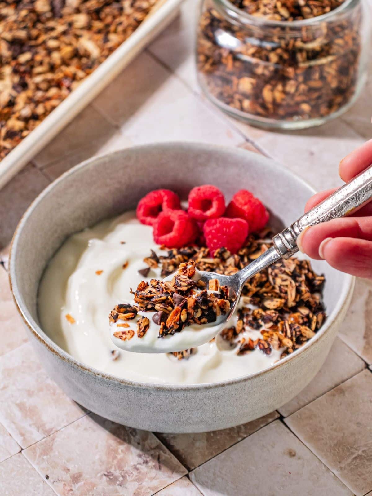 A spoon scooping up some chocolate granola in yogurt.