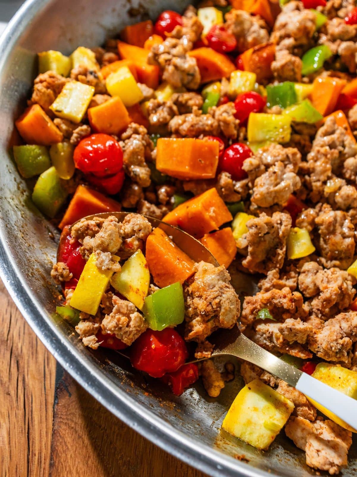 A spoon scooping up some chorizo hash from a pan.