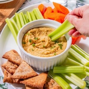 Garlic hummus being scooped up with a celery.