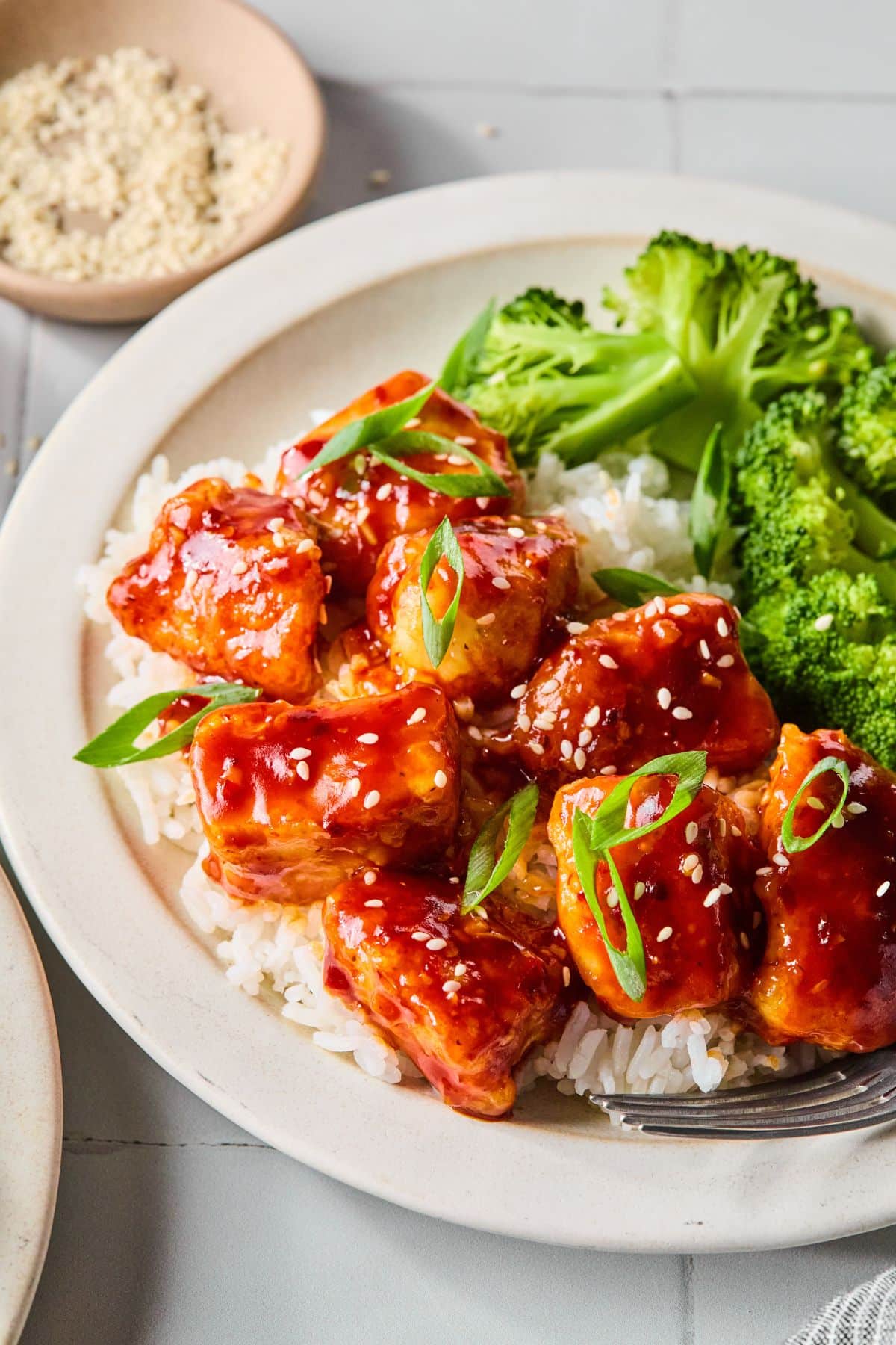 A plate with General Tso's chicken over rice and a side of broccoli.