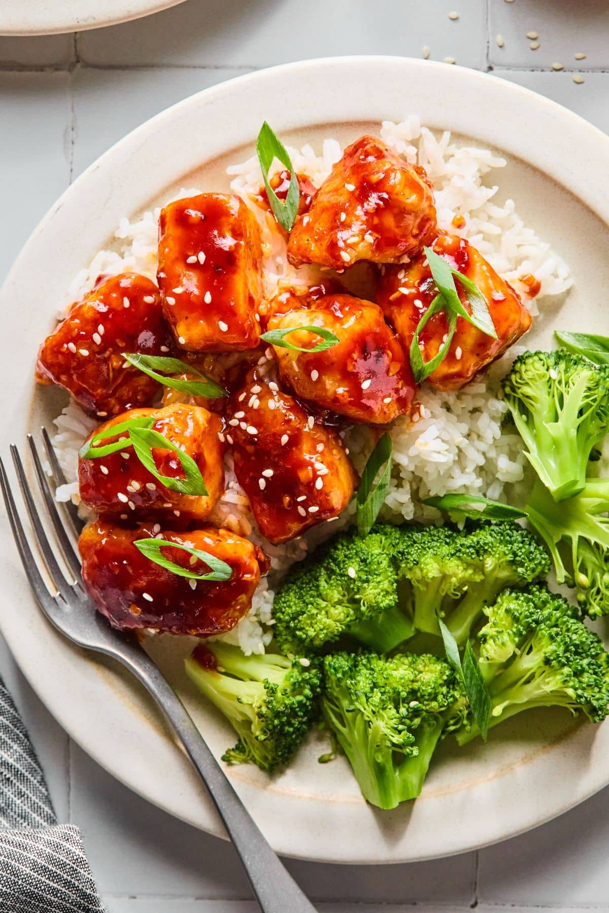 General Tso's chicken over rice with sesame seeds and green onions on top.