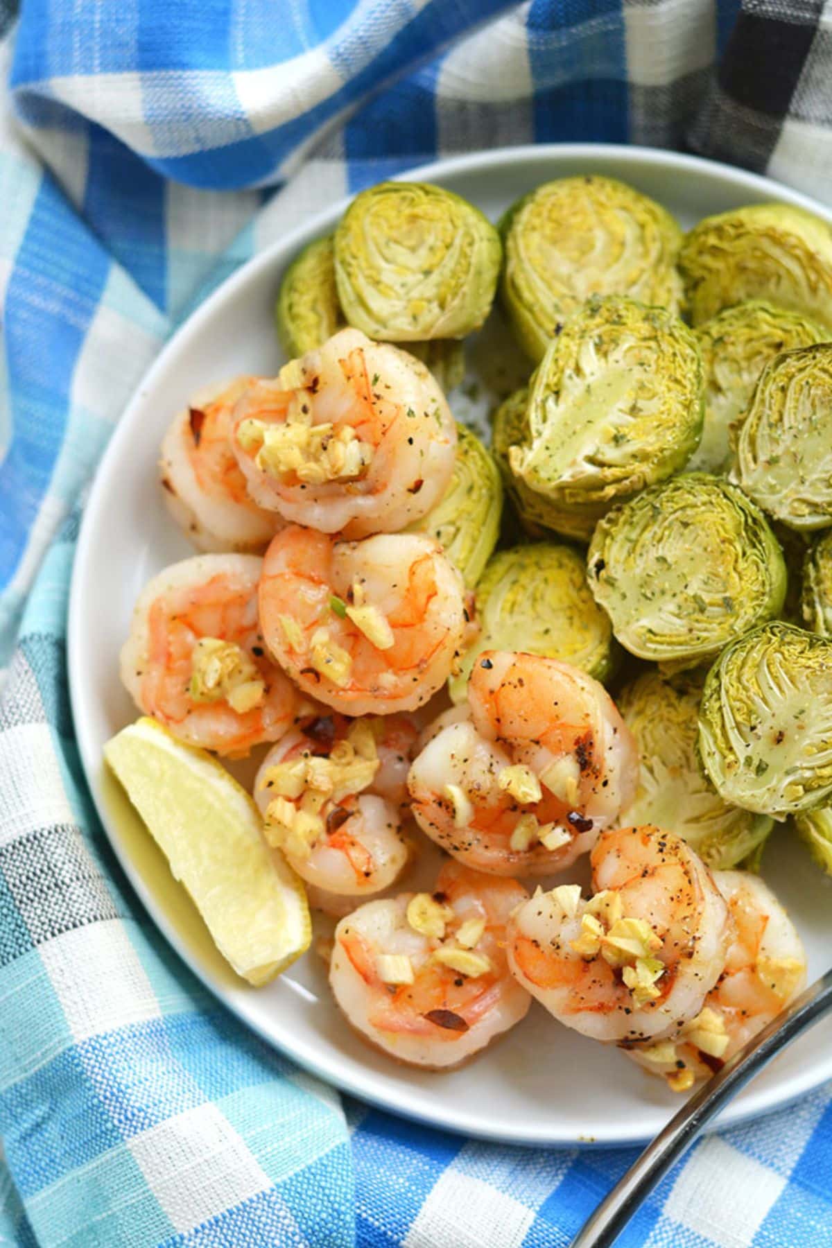 A plate with sheet pan shrimp with garlic on top.