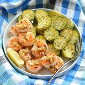 Sheet pan shrimp on a plate with a fork on the side.