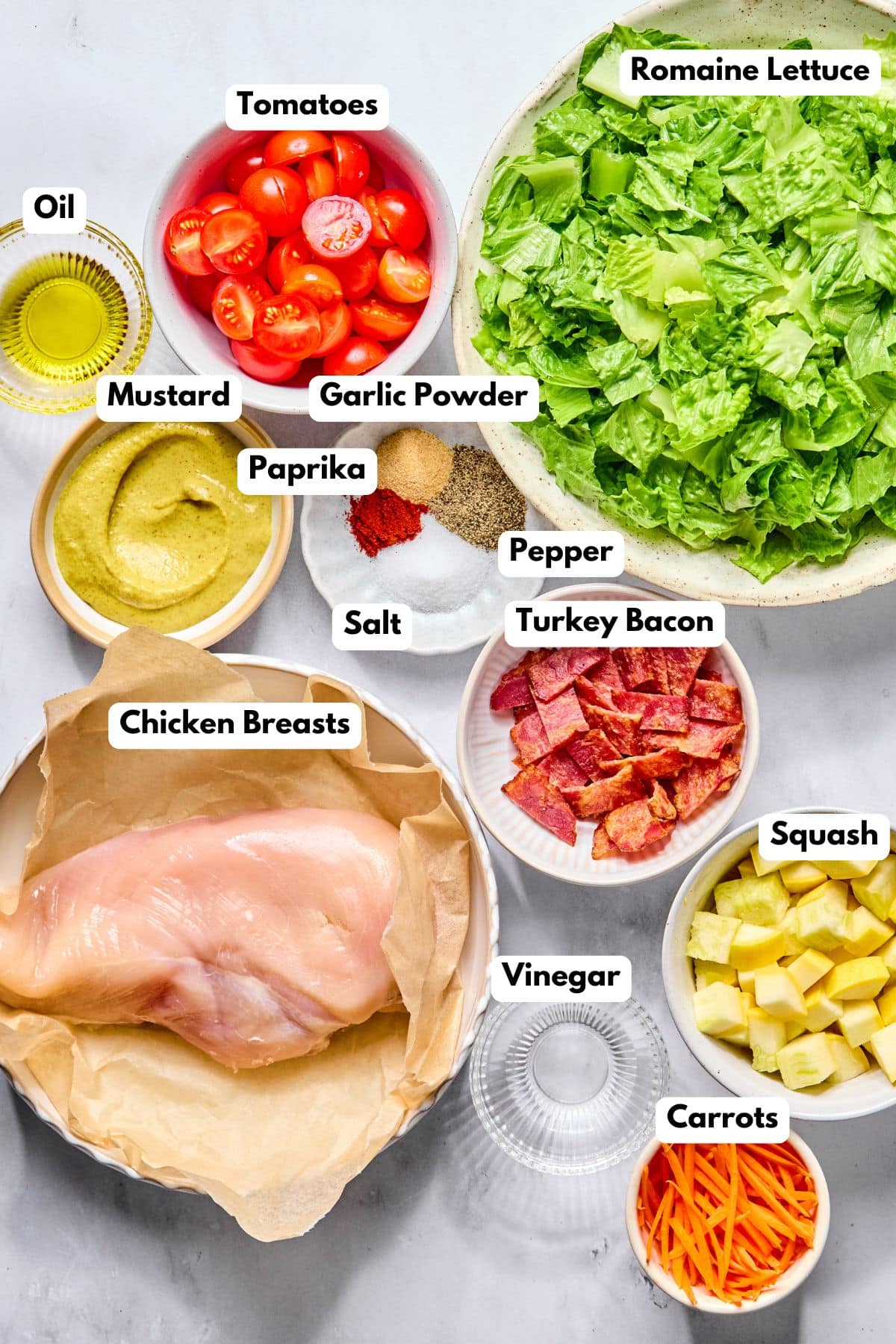 Ingredients to make this BLT chicken salad in bowls on a table.