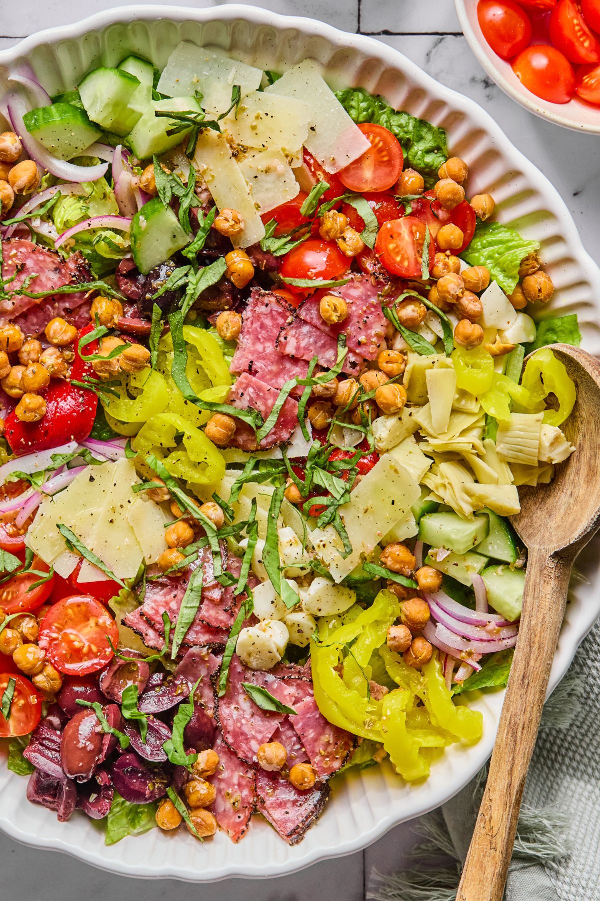 A salad with salami and cheese on a white plate.