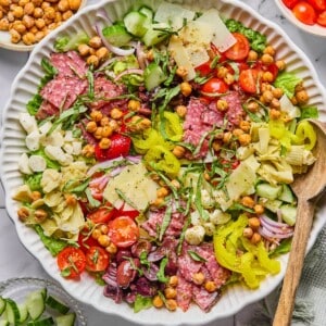 Chopped antipasto salad in a bowl with a wooden spoon on the side.