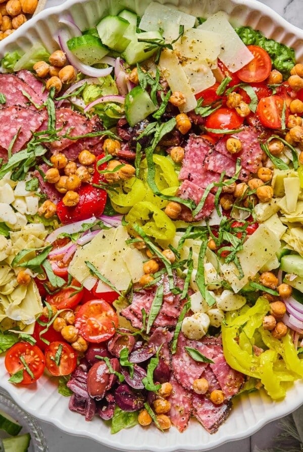 Chopped antipasto salad in a bowl with a wooden spoon on the side.