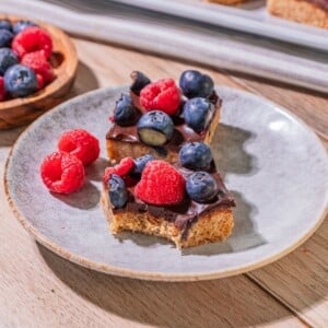 Gluten free berry bars with a bite taken out of one bar on a plate.