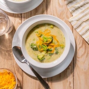 Healthy broccoli soup with cheddar cheese on top in a bowl.