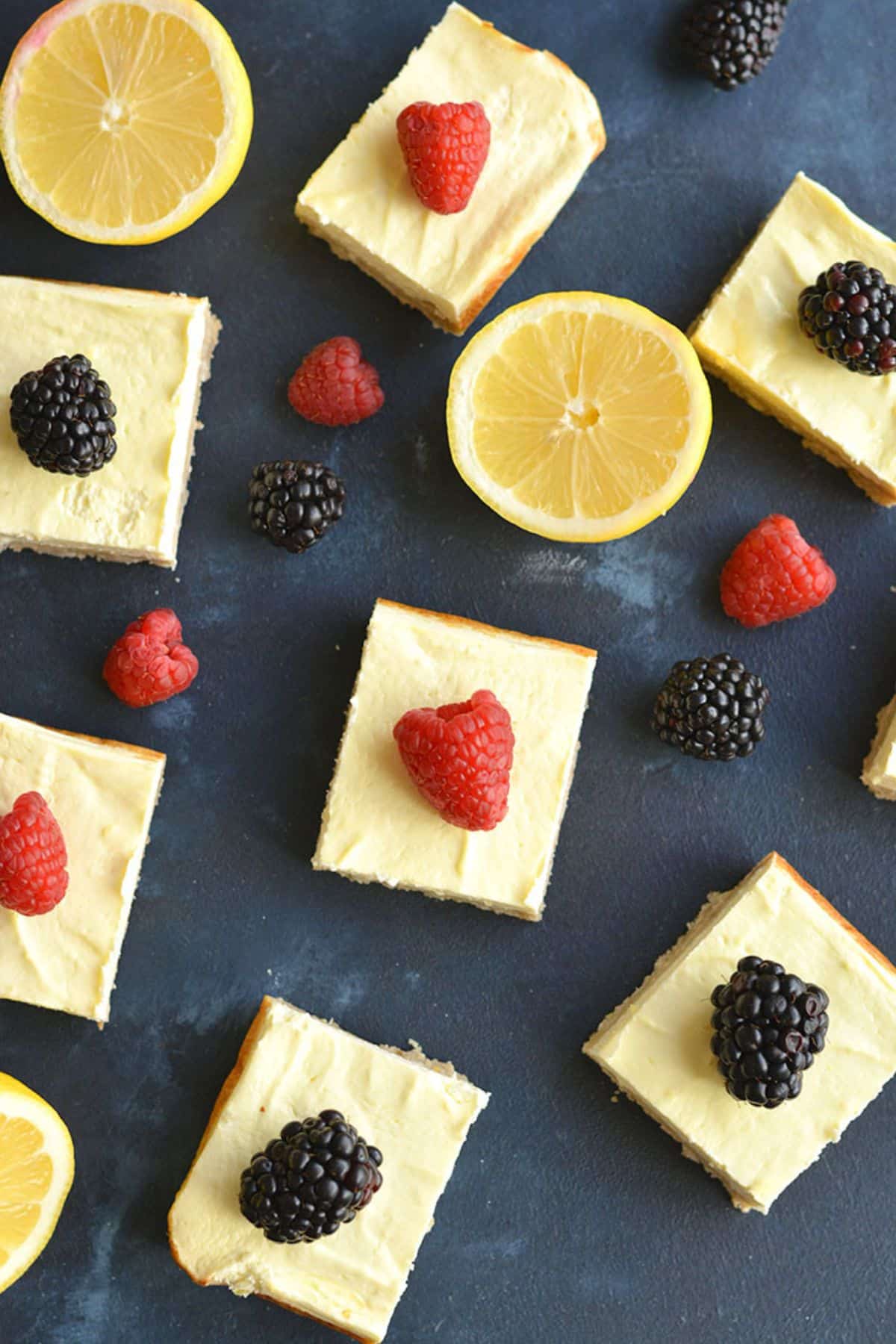 Healthy lemon bars garnished with fresh lemon and berries.