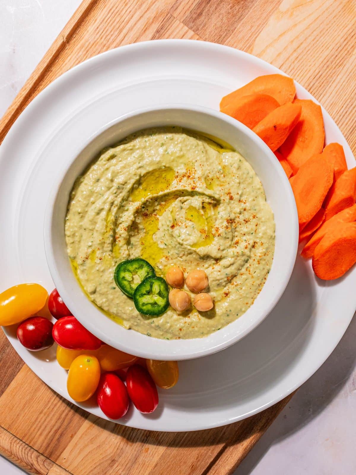 The hummus poured into a bowl and topped with chickpeas and jalapeno slices.