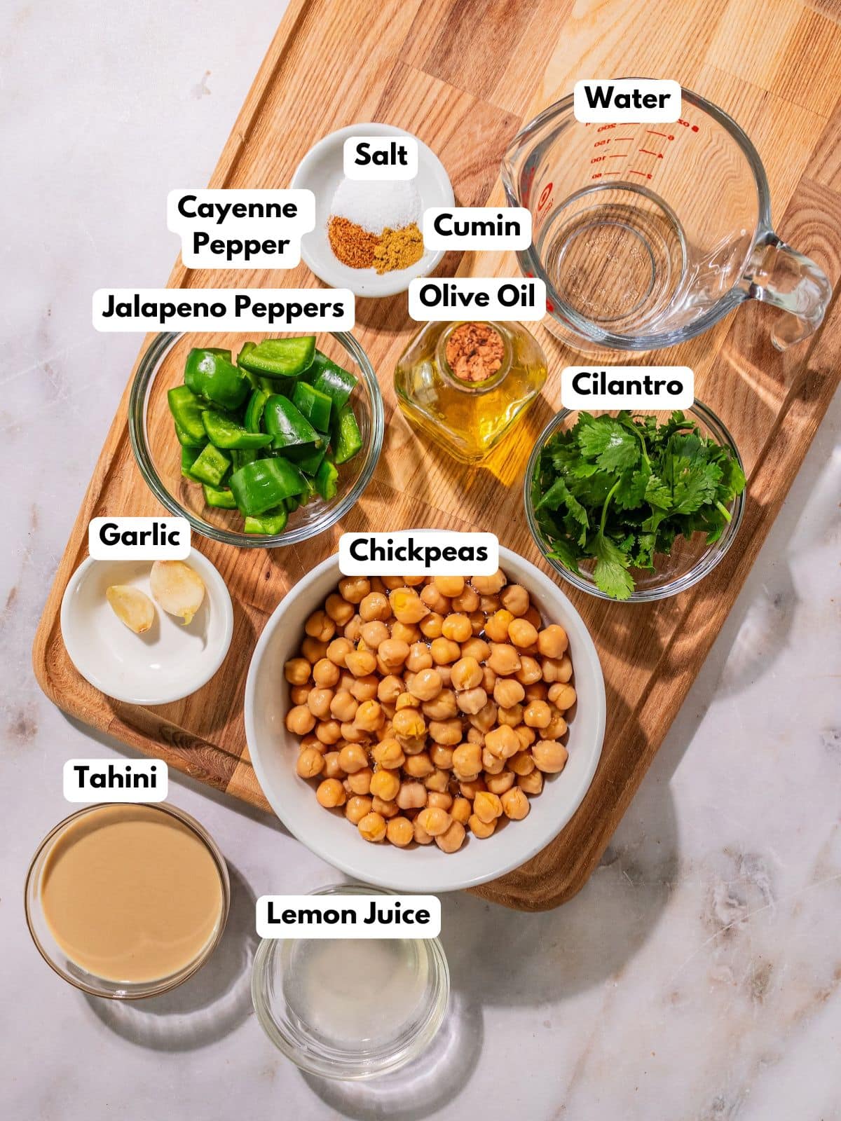 Ingredients to make this jalapeno hummus in bowls on a table.