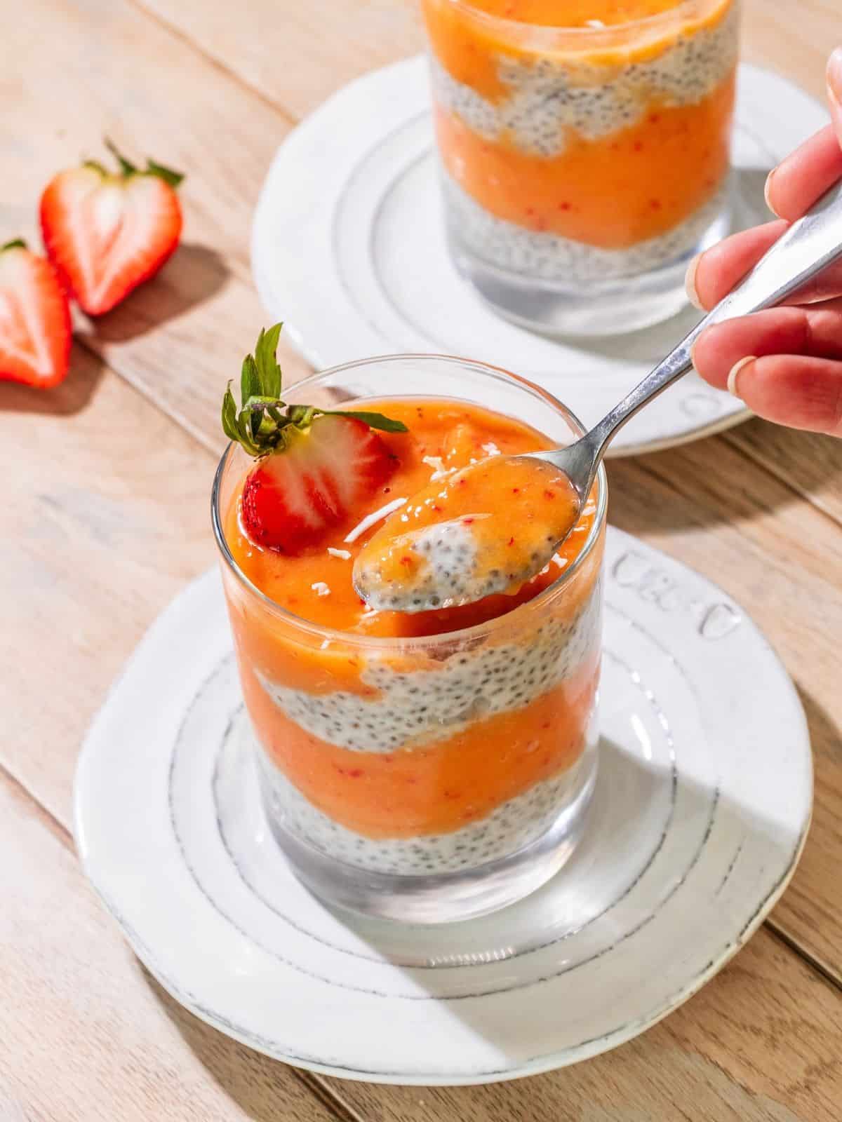 A spoon taking out some chia pudding with mango puree.
