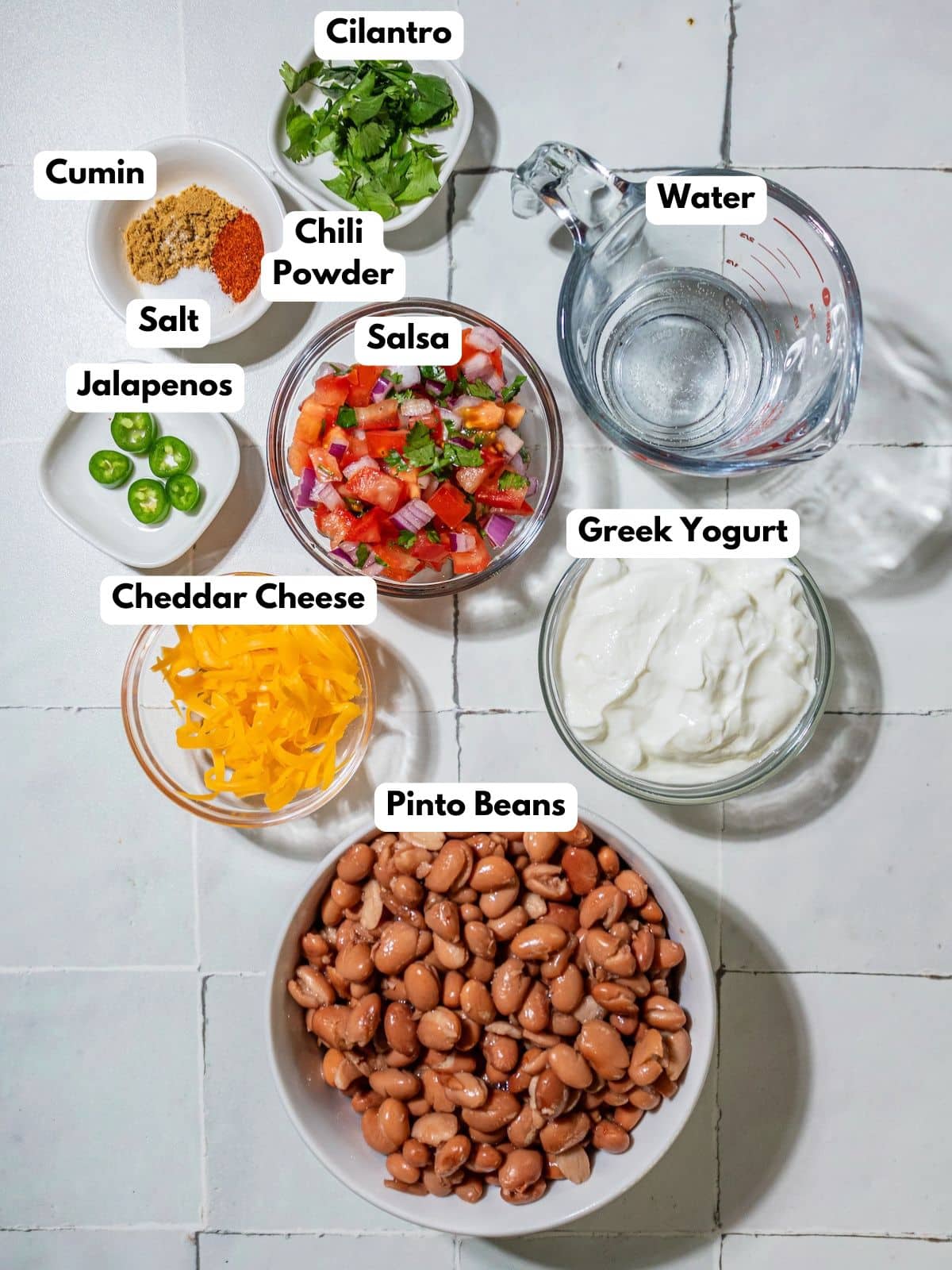 Ingredients to make this bean dip in bowls on a table.