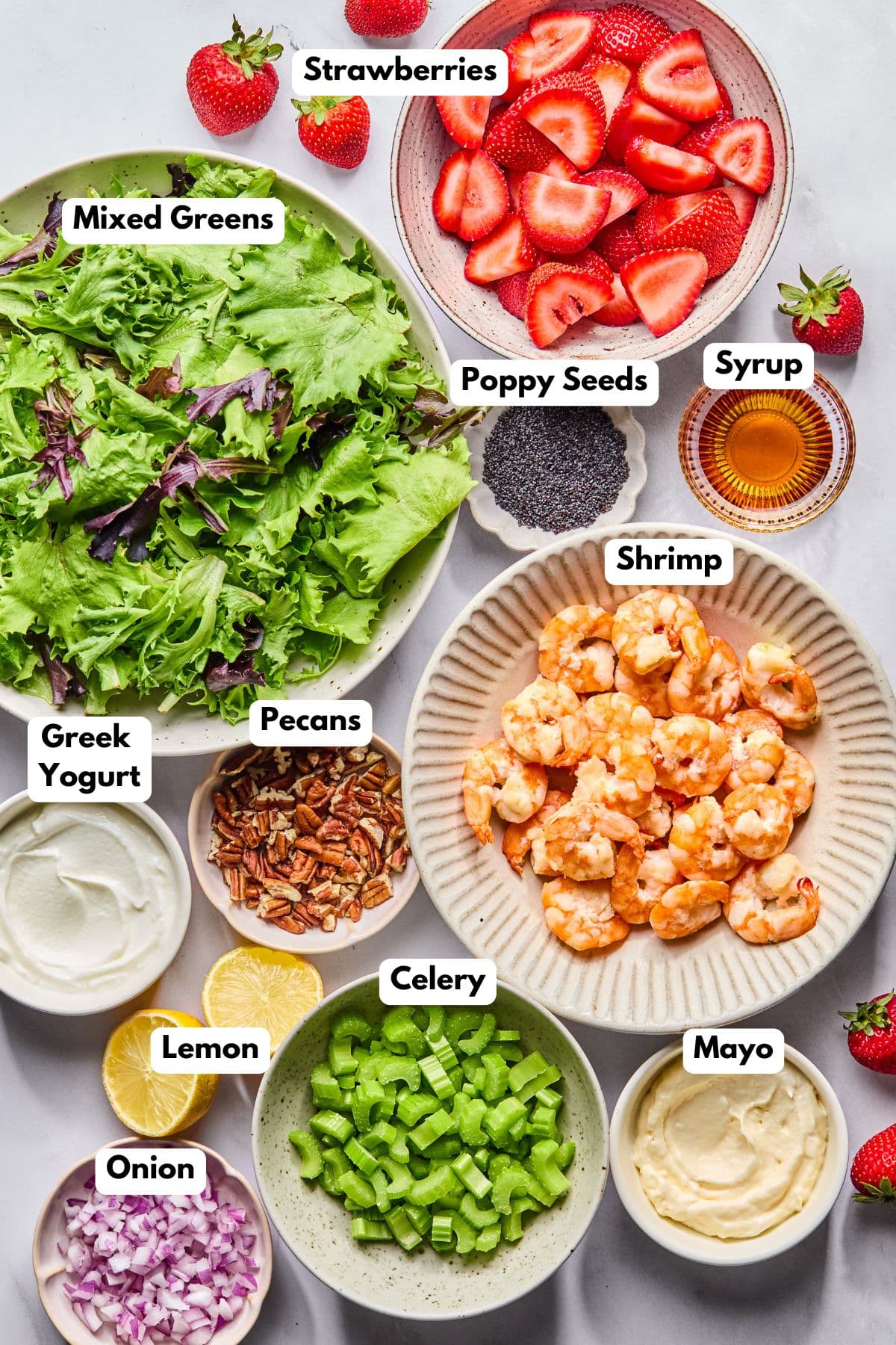 Ingredients to make this strawberry and shrimp salad in bowls on a table.