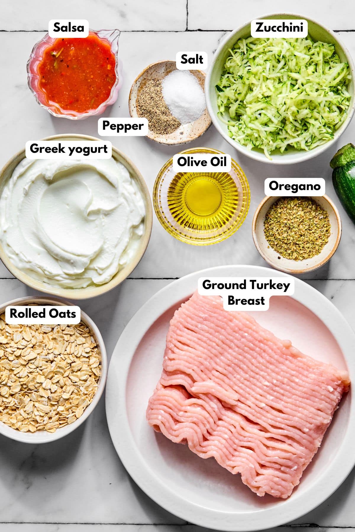Ingredients to make zucchini turkey burgers in bowls on a table.