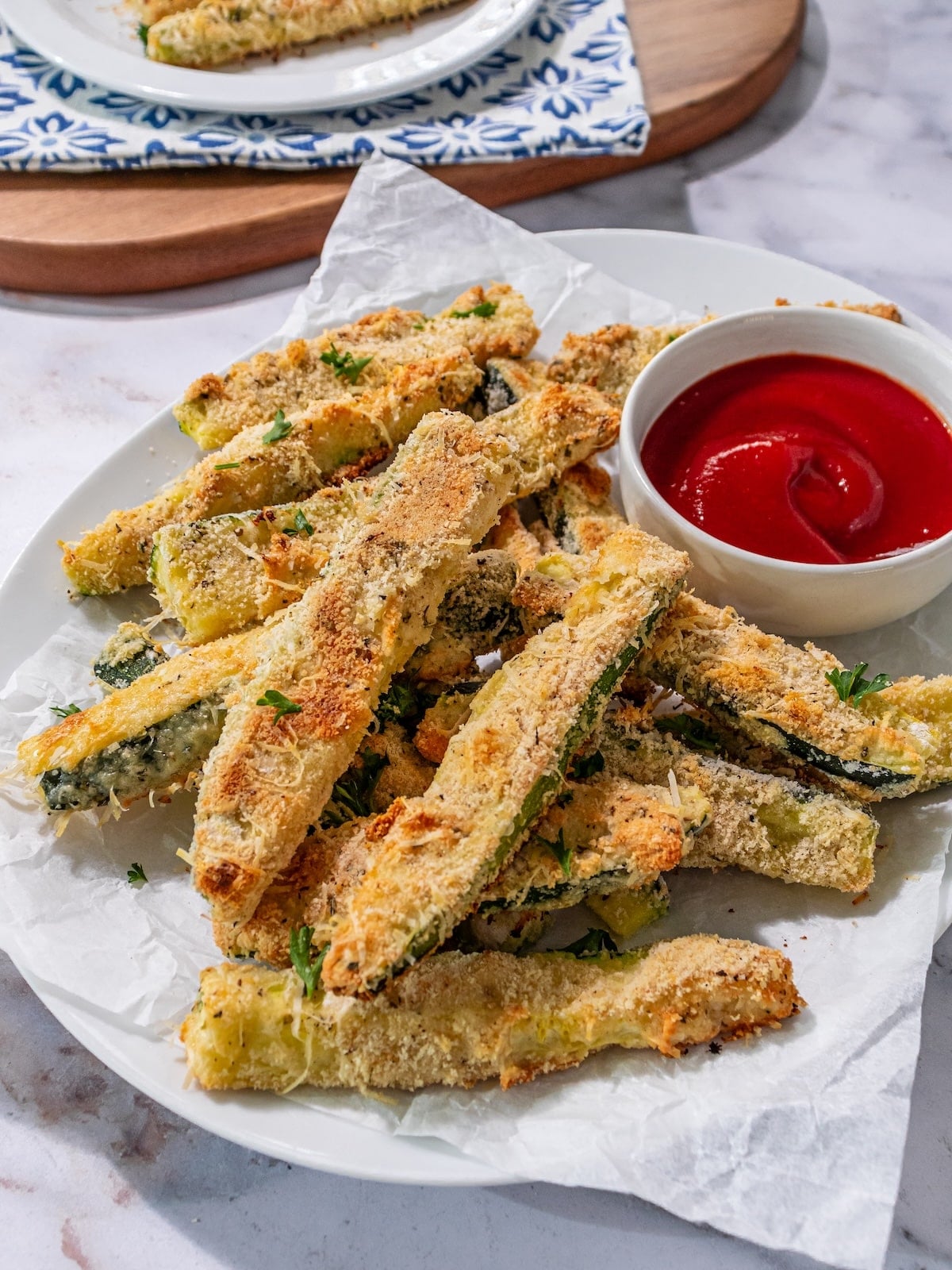 Baked zucchini fries on a plate with a small bowl of ketchup.